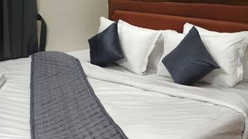Een net opgemaakt bed met een gewatteerde deken, een houten hoofdbord en meerdere kussens.