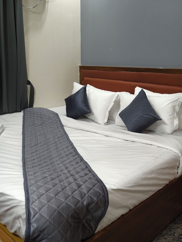A neatly made bed with a quilted blanket, a wooden headboard, and multiple pillows.