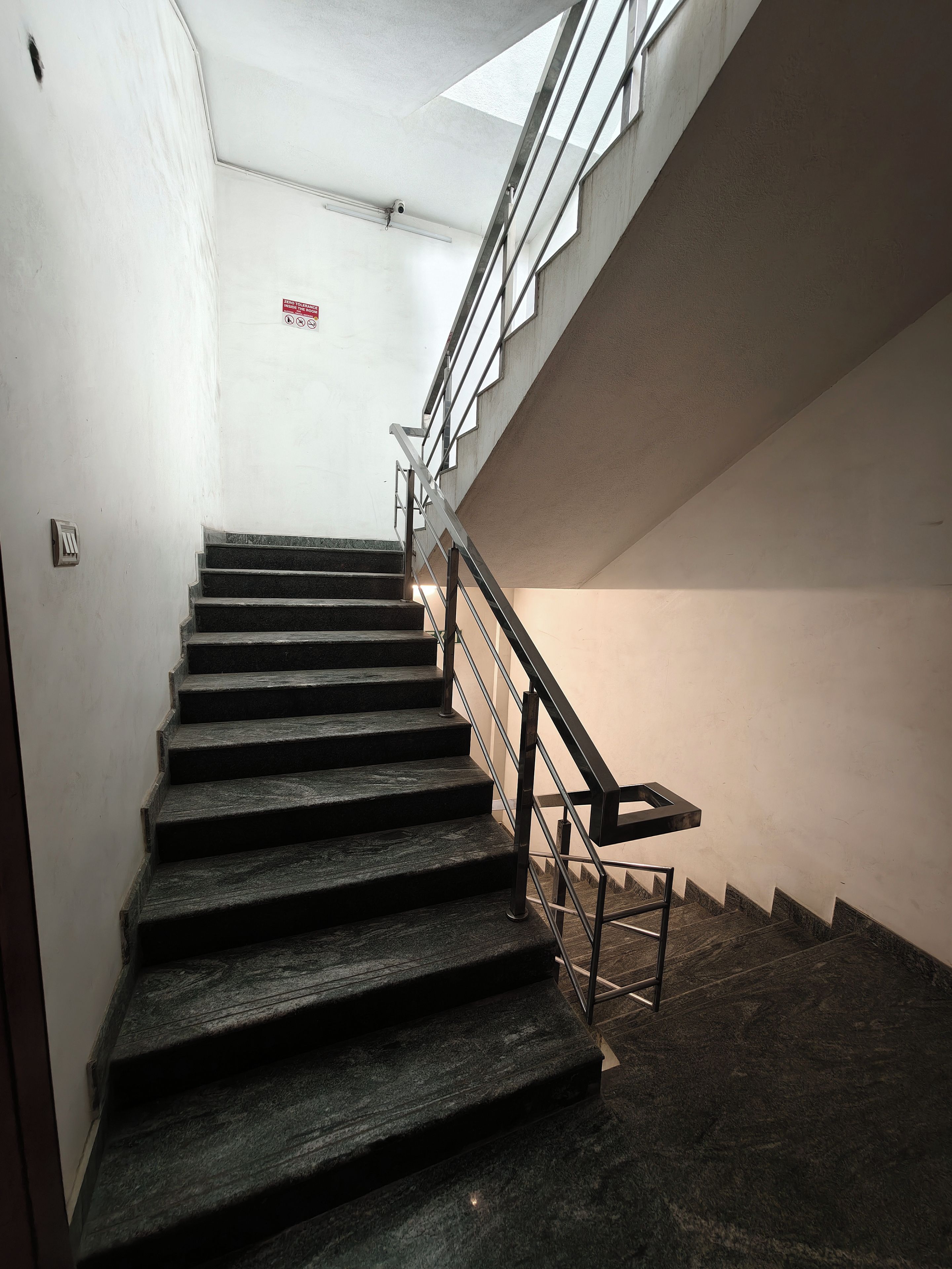 Una escalera con barandales de metal y pasamanos, que conduce a un piso superior.