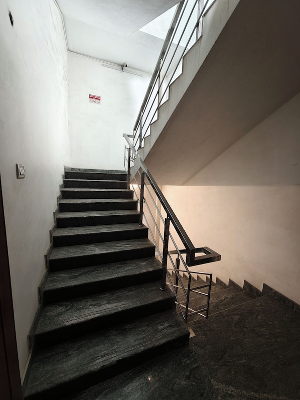 Un escalier avec des rampes et une main courante en métal, menant à l’étage supérieur.