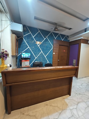 A reception desk with a computer monitor, a security camera, and a sign indicating a smoking area.