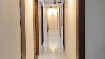 A corridor with a polished marble floor, wooden doors, and recessed lighting.