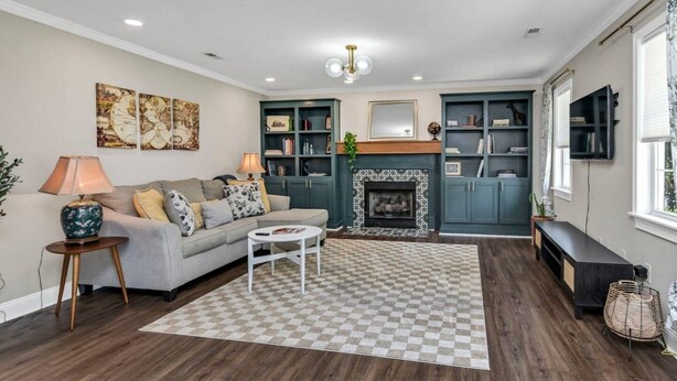 A living room with a fireplace, a sofa, a coffee table, and a bookshelf. - Cottontown Cottage | Fenced Yard & Covered Patio (Columbia)