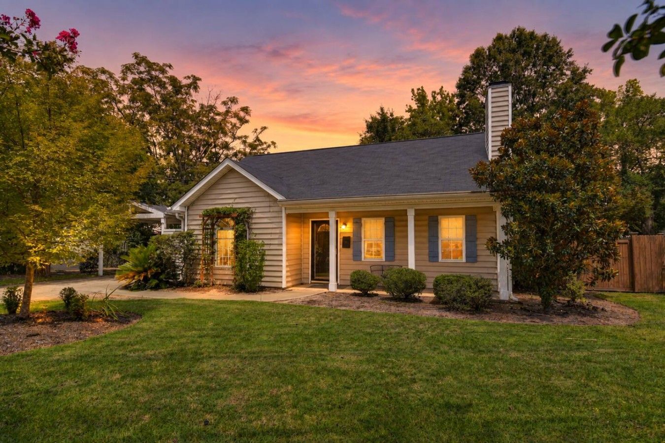 A single-story house with a covered porch, a chimney, and a well-maintained lawn.