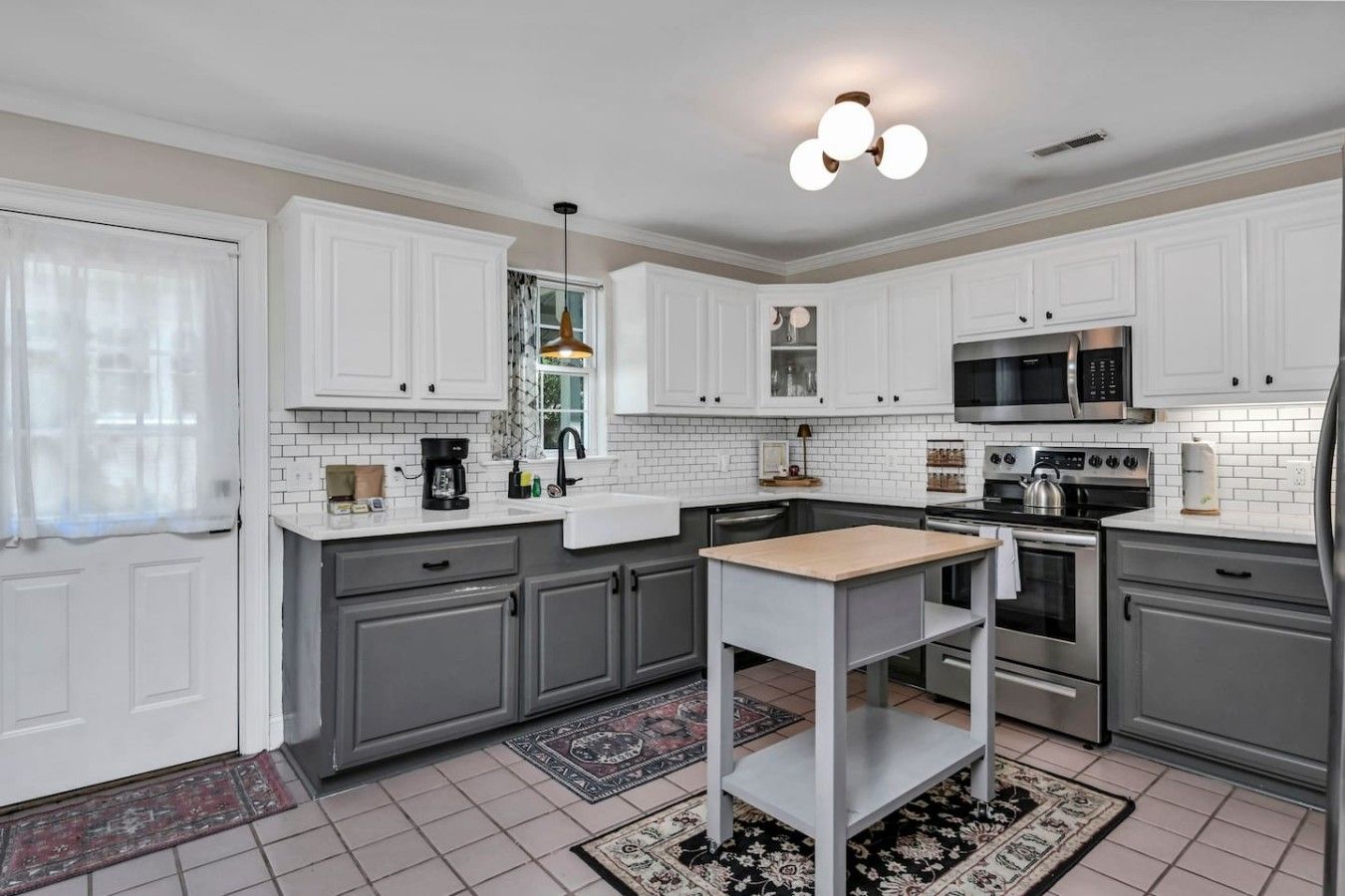 A modern kitchen with white cabinetry, a central island, and a microwave.