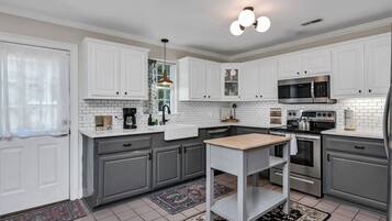 A modern kitchen with white cabinetry, a central island, and a microwave.