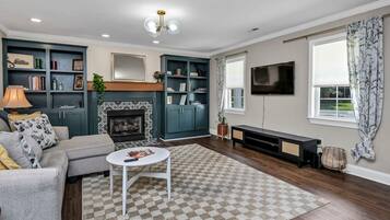 A living room with a fireplace, a sofa, a coffee table, and a TV.