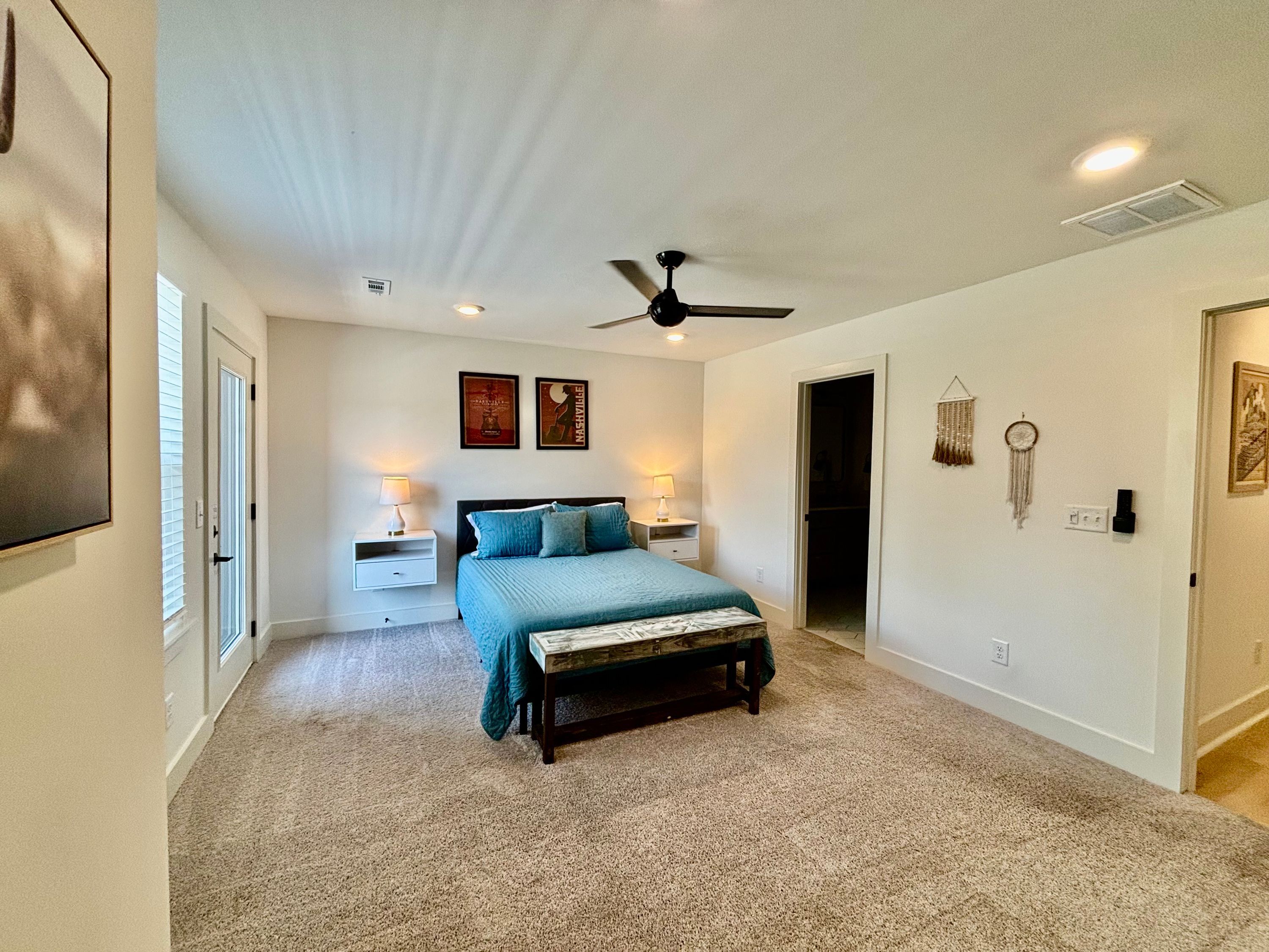 A bedroom with a bed, nightstands, a ceiling fan, and wall decorations.