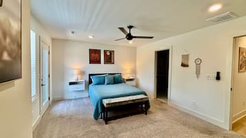 A bedroom with a bed, nightstands, a ceiling fan, and wall decorations.
