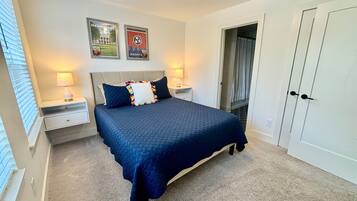 A bedroom with a bed, two nightstands, a lamp, a door, and two posters on the wall.