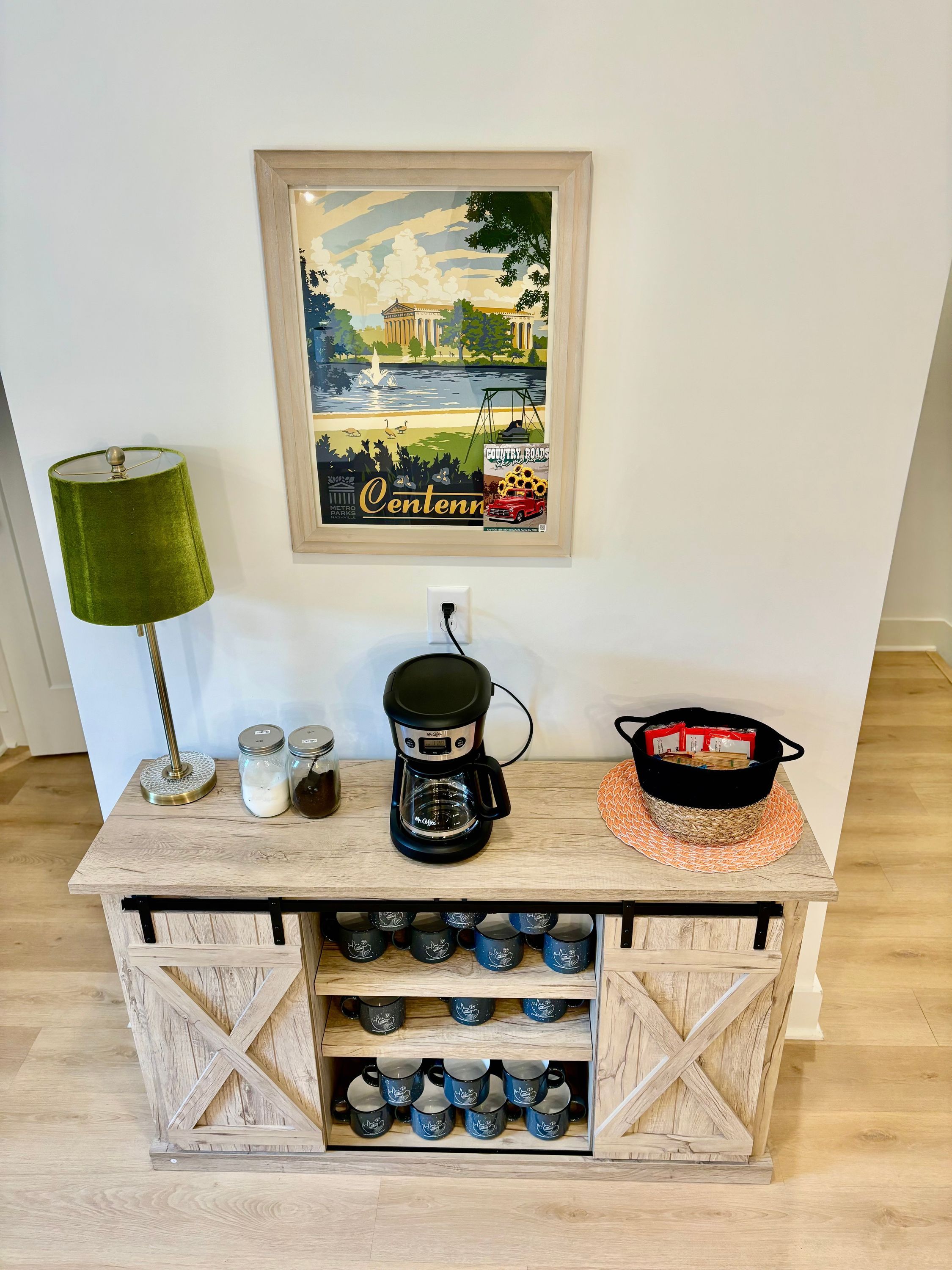 A wooden coffee station with a coffee maker, jars, and a basket.