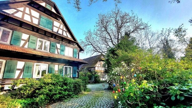 Een historisch vakwerkhuis met een straatje van keien dat naar een tuin leidt.