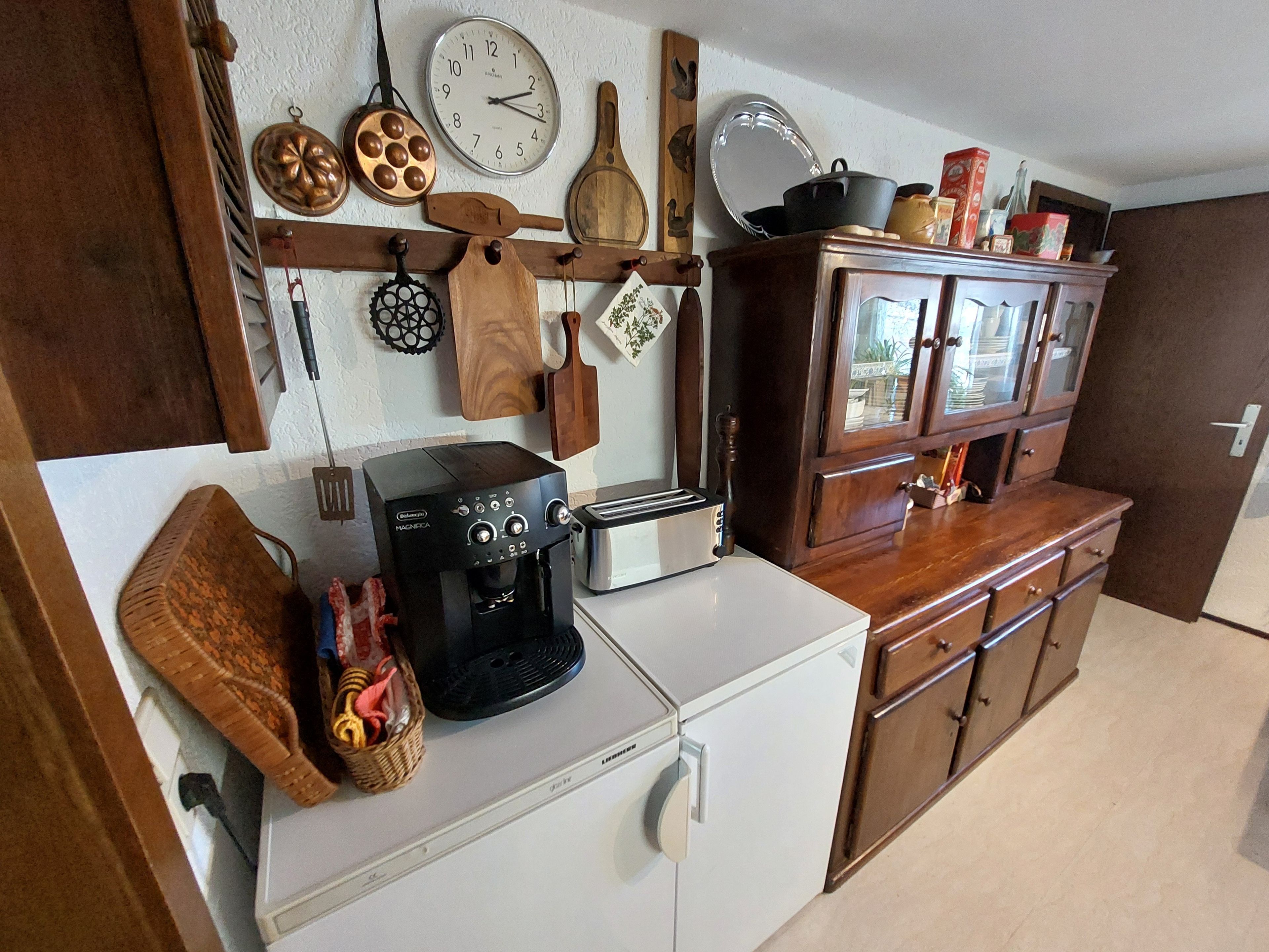 Une cuisine équipée d’une machine à café, d’un grille-pain et de meubles de rangement en bois.