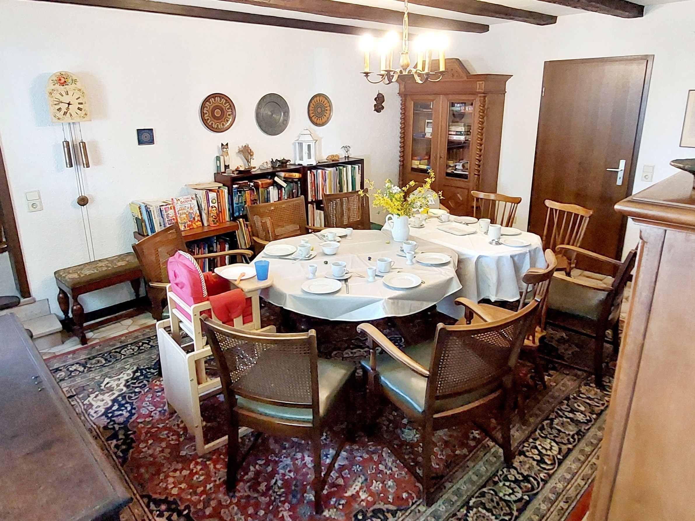 Un coin repas avec une table ronde dressée pour quatre personnes, entourée de chaises en bois.