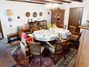 A dining area with a round table set for four, surrounded by wooden chairs.