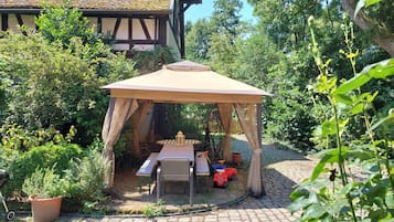 Un jardin agrémenté d’un kiosque, d’une table, de chaises et d’une plante en pot.