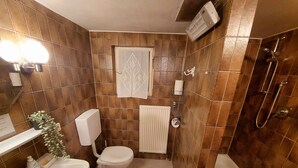 Een badkamer met een bad, toilet en douche.
