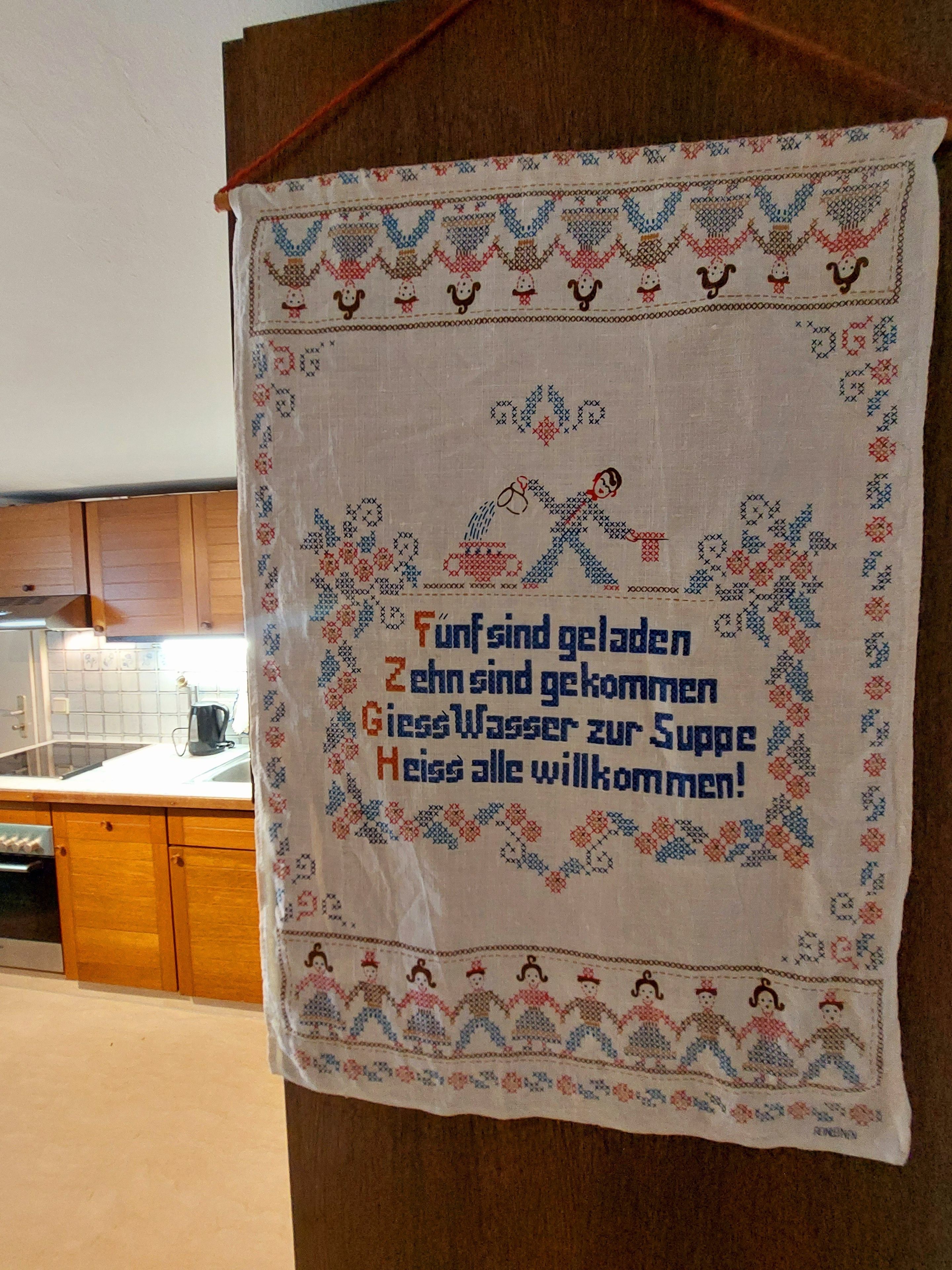Eine Küche mit Holzausstattung und einem Küchentuch mit deutschem Text.
