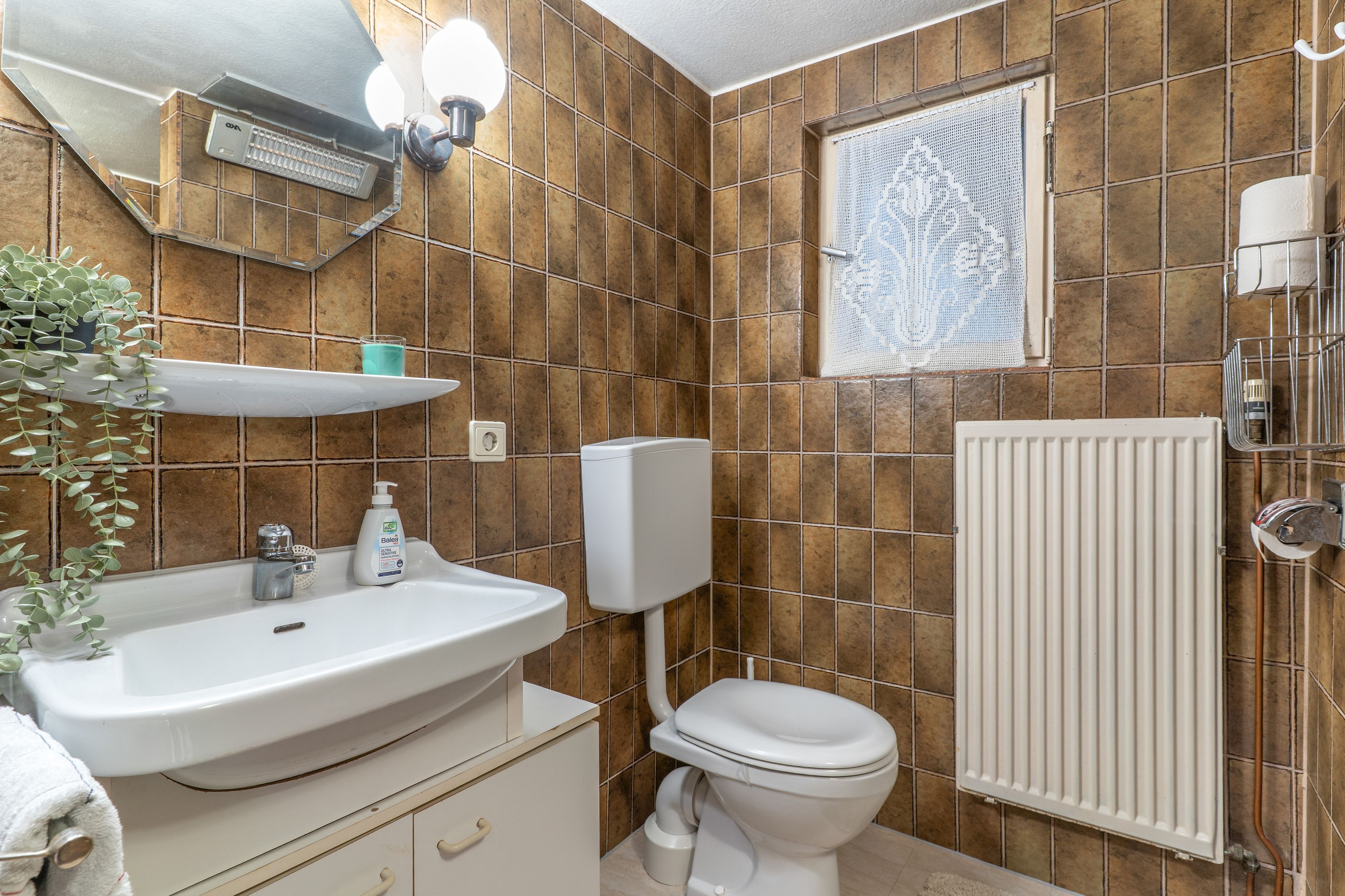 A bathroom with a white sink, toilet, and radiator.