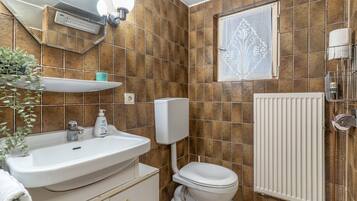 A bathroom with a white sink, toilet, and radiator.