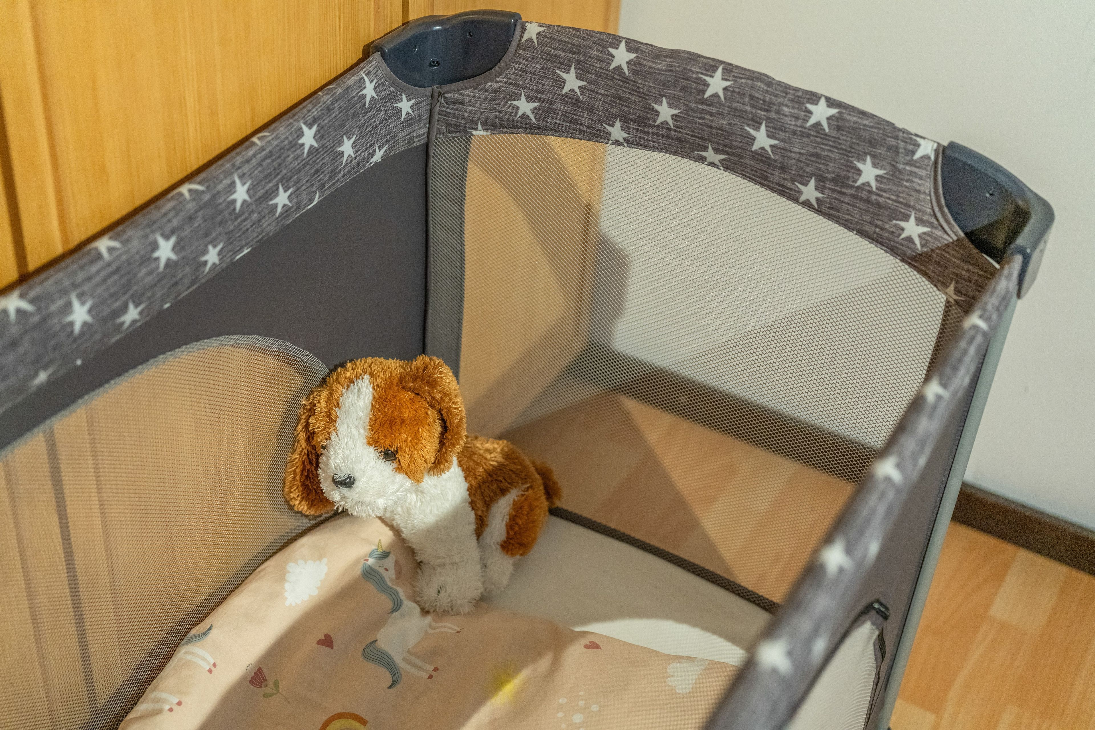 A corner of a room with a crib featuring a star pattern on the side.