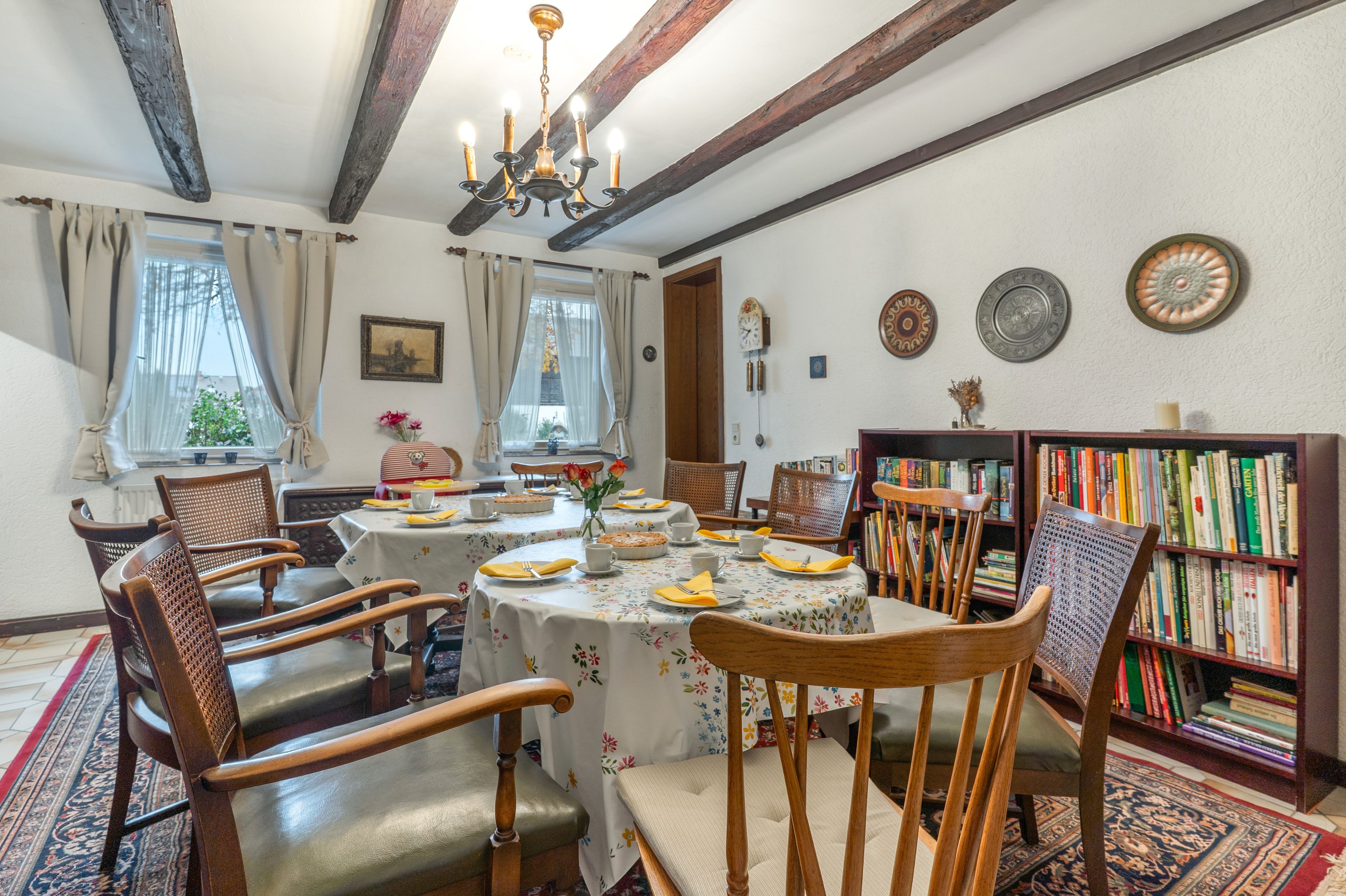 Une salle à manger avec une table ronde dressée pour six personnes, entourée de chaises en bois.