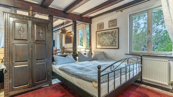 Een klassieke kamer met een hemelbed, een grote houten garderobe en een raam met uitzicht op bomen.
