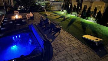 A patio area with a hot tub, outdoor seating, and a well-maintained lawn.
