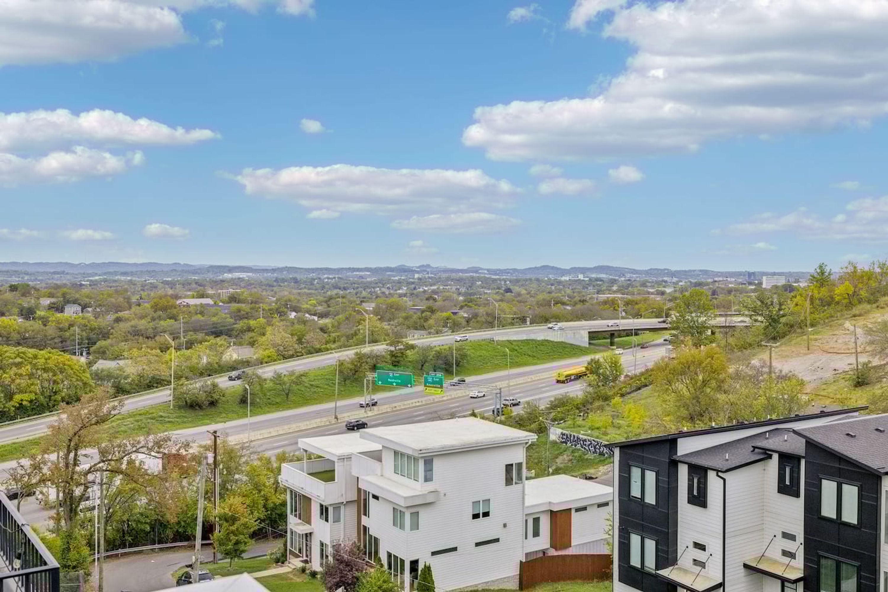 A residential area with modern houses, a highway, and a clear sky.