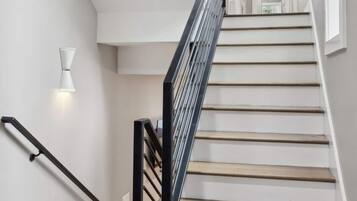 A staircase with wooden steps and a black handrail, leading to an upper floor.