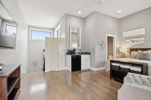 A modern bedroom with a large bed, a bedside table, a dresser, and a built-in desk with a chair. There is a window providing natural light and a view of the outside. - Hottub 2milestobway 3kbeds 5futons Safe (Nashville)