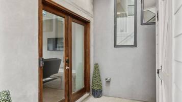 A narrow hallway with a sliding glass door leading to a room, a small potted plant, and a round doormat.