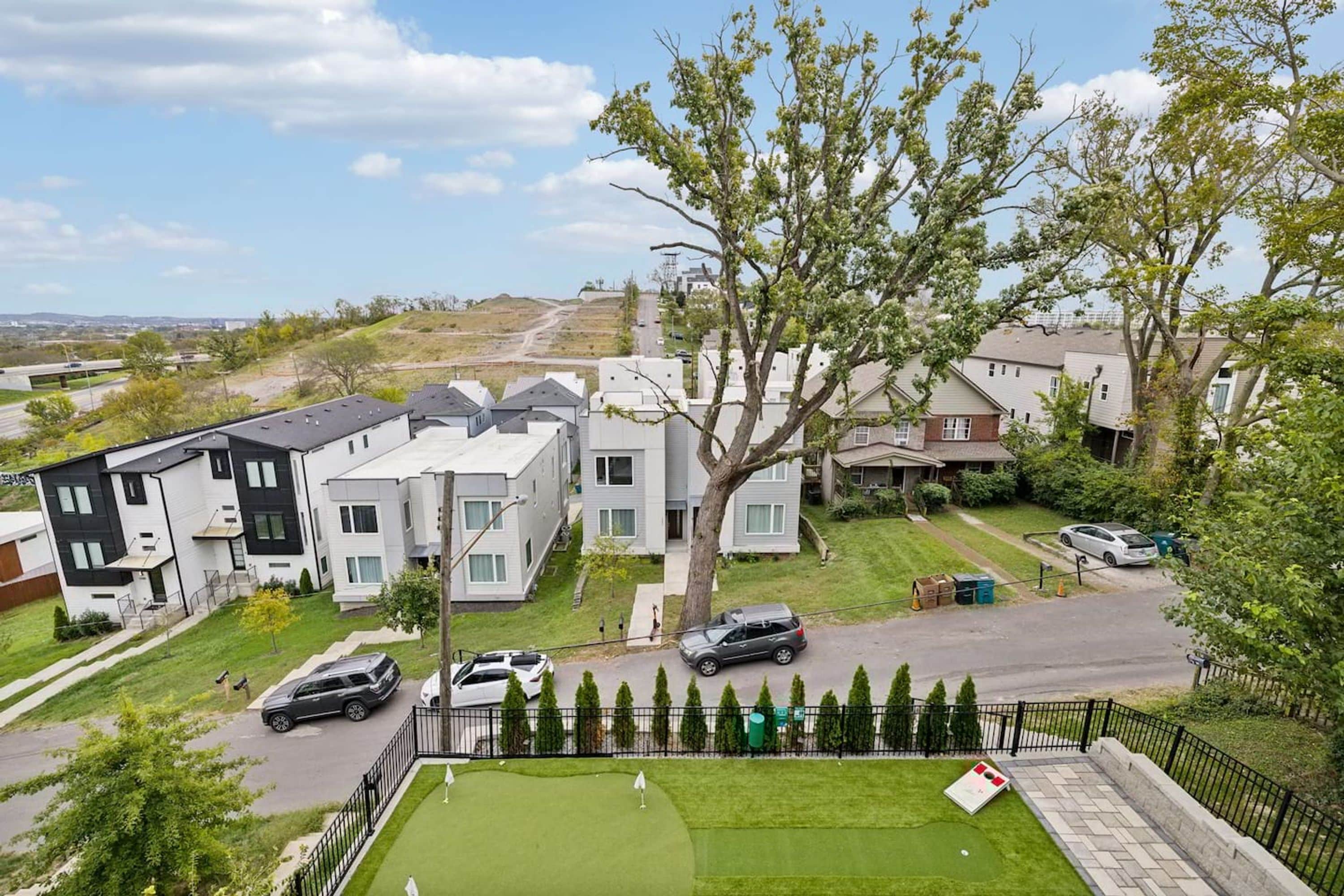 A residential area with modern houses, a well-maintained lawn, and a clear sky.