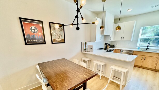Eine moderne Küche mit weißen Schränken, einem Holztisch und einer Bar.