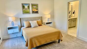 A bedroom with a bed, two nightstands, a ceiling fan, and a bathroom visible through an open door.