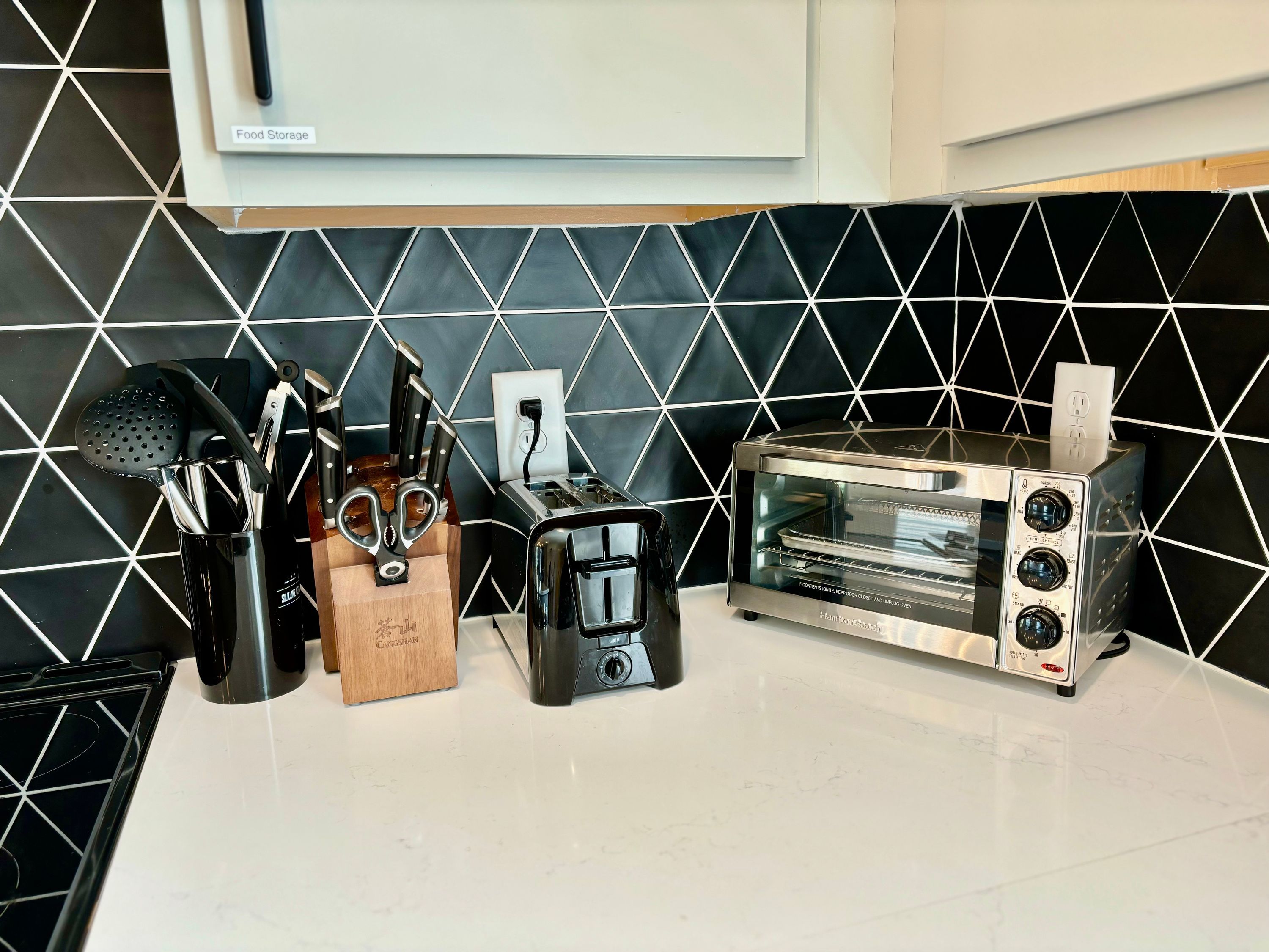 Eine Küche mit schwarz-weißer Küchenrückwand, einem Toaster und einem Messerblock.