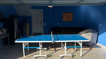 A ping pong table in a garage with a blue wall and a door marked 112.