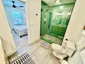A bathroom with a shower, toilet, and a bed in the adjacent room. - Closetobroadwayairportoprymillsgameroom (Nashville)