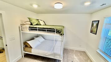 Een slaapkamer met een stapelbed, een raam en een ingelijst kunstwerk aan de muur.