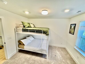 A bunk bed room with a window and a framed picture on the wall.
