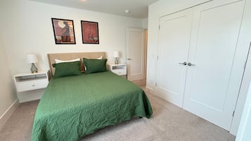 Un dormitorio con cama, dos mesitas de noche, un armario y dos carteles enmarcados en la pared.