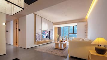 A modern living room with a sofa, a coffee table, and a TV mounted on a wall.