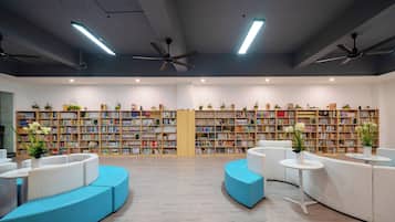Une bibliothèque moderne dotée d’étagères, d’espaces de lecture et de ventilateurs de plafond.