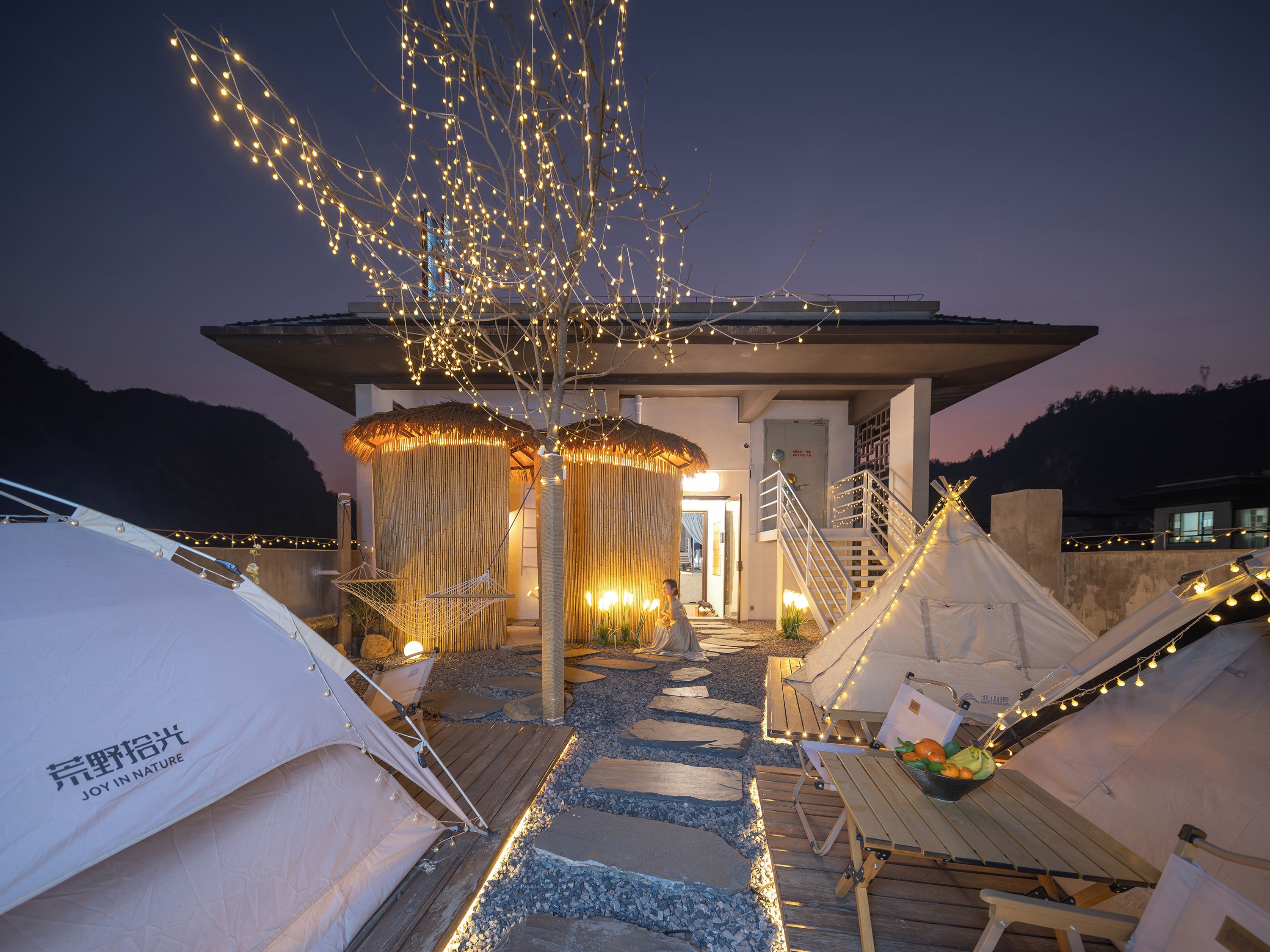 A campsite with tents, a wooden deck, and string lights.