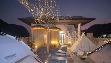 A campsite with tents, a wooden deck, and string lights.