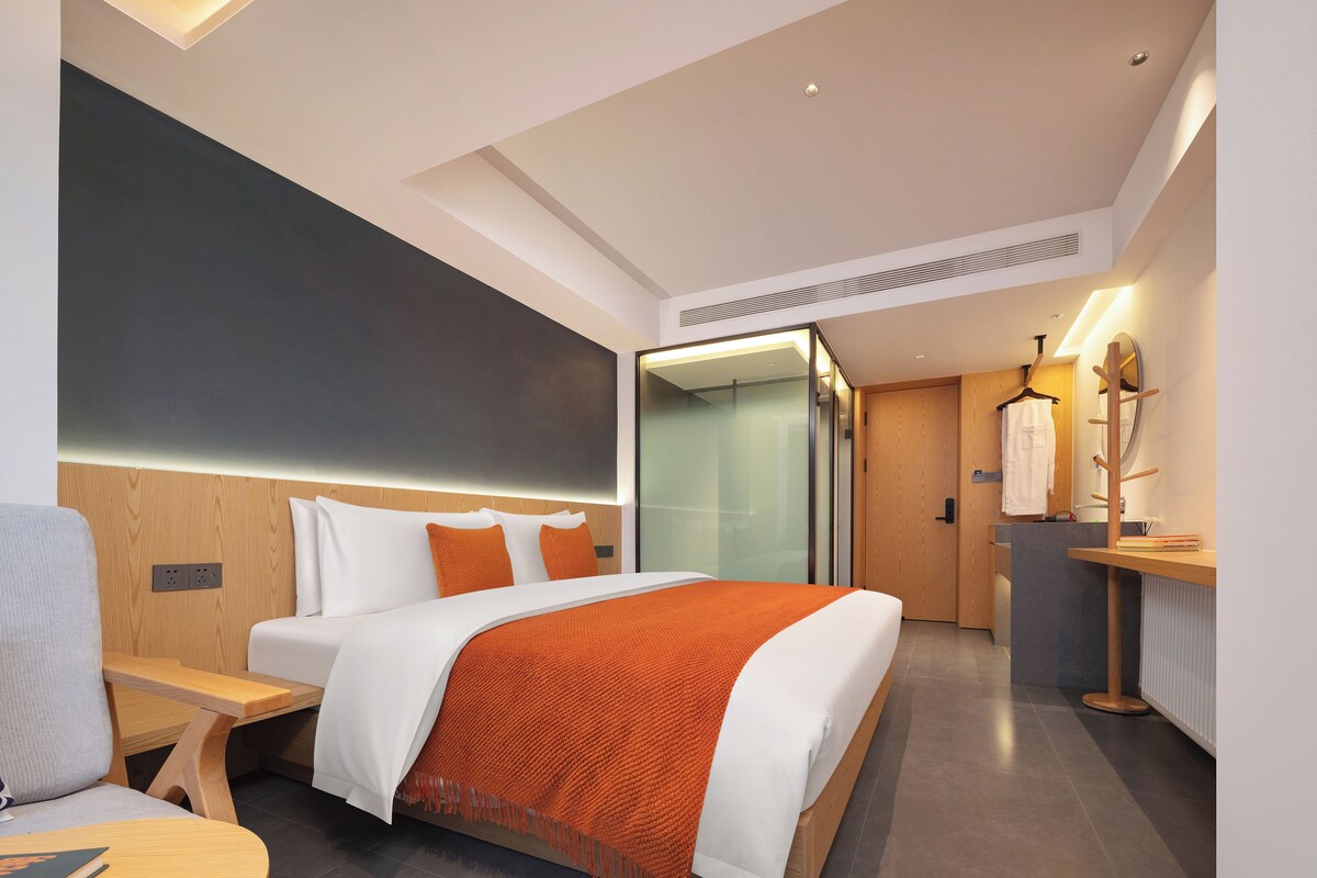 Una habitación de hotel moderna con una cama grande, una mesita de noche y un espejo.