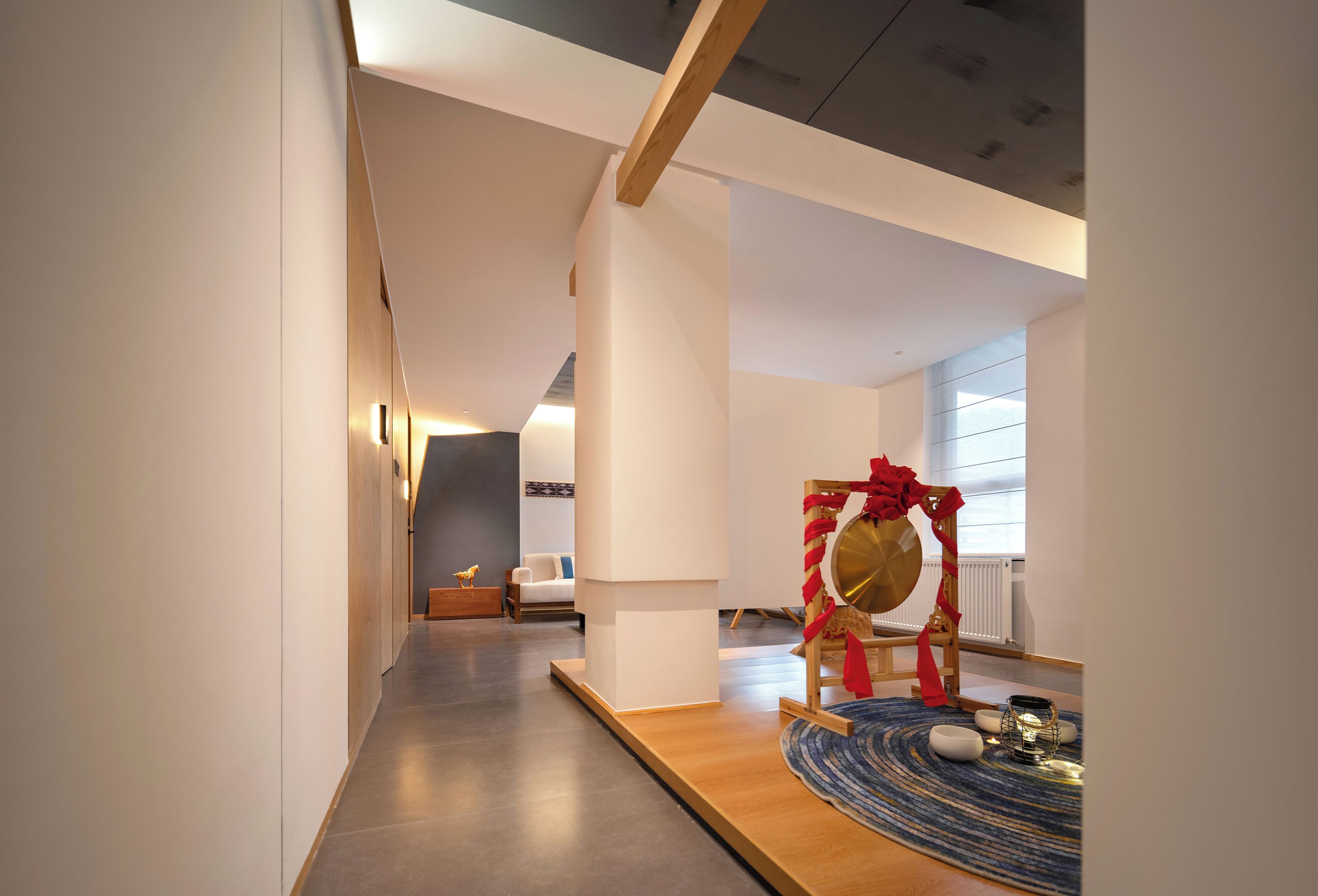 A modern interior with a hallway leading to a room with a bed and a decorative chair with a red bow.