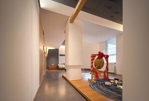 Un interior moderno con un pasillo que conduce a una habitación con una cama y una silla decorativa con un lazo rojo.