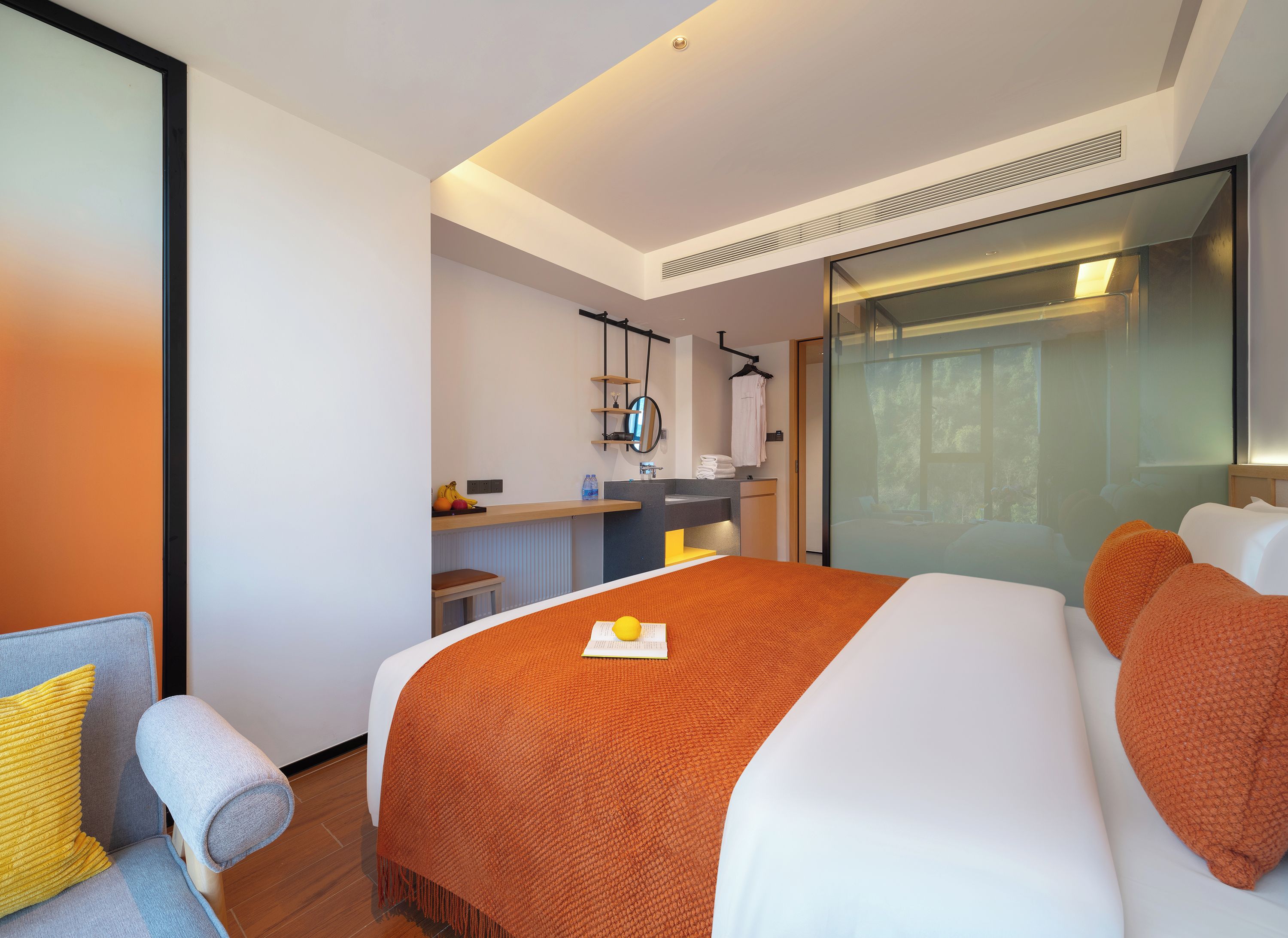 Quarto de hotel com cama, escrivaninha, cadeira e banheiro.