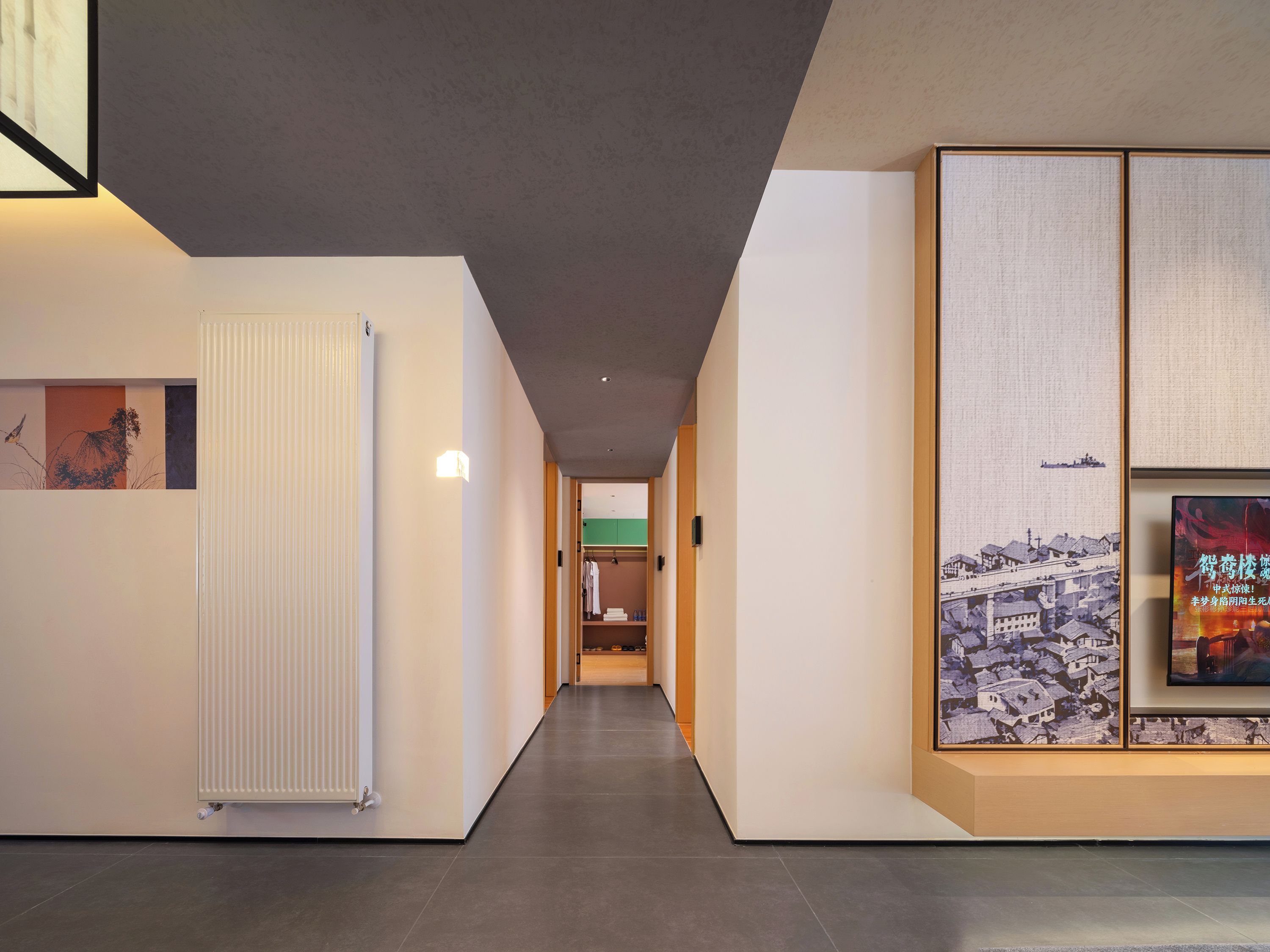 A hallway with a radiator, a framed picture, and a poster on the wall.